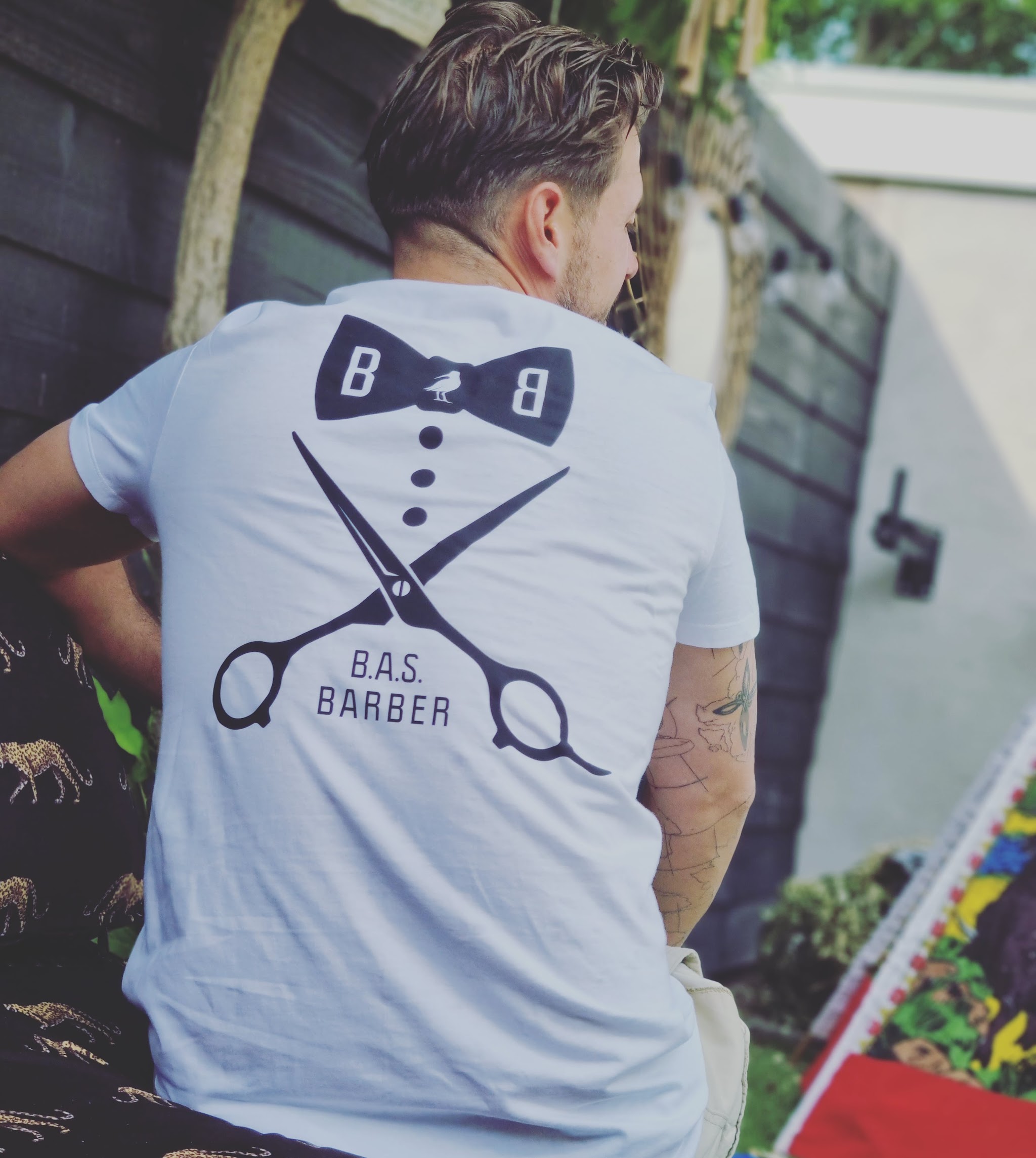 Bas van achteren in een wit shirt met het B.A.S. barber-logo